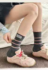 Detailed close-up showing the elastic pink lettuce trim and lace patch on charcoal crew socks