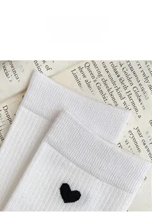 Detailed close-up of white crew socks with small black heart patterns and ribbed cuffs