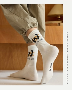Detail of white cotton crew sock with black letters and graphic knit texture