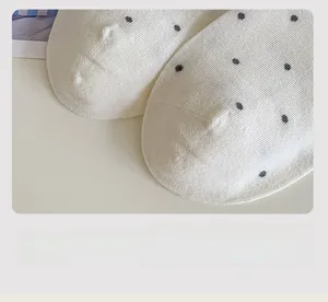 Detail of white cotton socks with black polka dots showing smooth toe seam construction