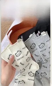 Close-up of cat-themed crew socks with cute fabric tags and meow pattern embroidery