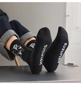 Detailed texture of black cotton crew socks with white SUSUFISH lettering and patterns