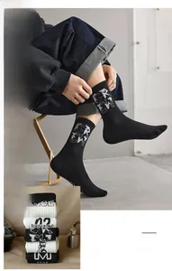 Close-up of ribbed knit crew socks with letter patterns and contrast black-white stitching