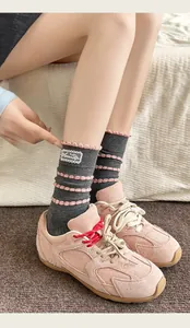 Detail of grey cotton socks with pink wavy stripes and lace logo patch with pink sneakers
