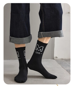 Detailed close-up of black mid-calf socks featuring gray letter M and 1988 knit pattern