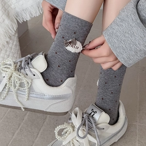 Grey designer crew socks with polka dots and ribbon bow detail shown on a model