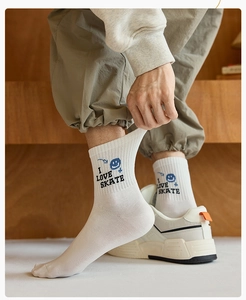Detail of white cotton crew socks featuring I LOVE SKATE text and blue smiley graffiti