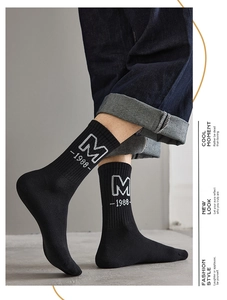 Detail of black ribbed crew socks featuring white M and 1988 letter embroidery