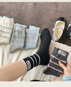 Detail of ruffle cuff cotton socks featuring elegant lace label and knit wave texture