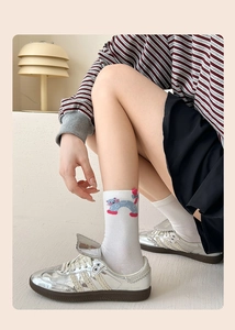 Detailed close-up of white crew socks with cartoon cat pattern and rainbow knit texture