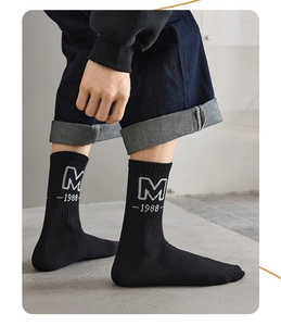Detail of black cotton sports sock featuring a grey M-1988 letter print with denim jeans