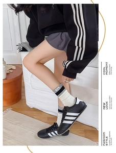 Detail of striped socks with brand label paired with three-stripe sporty sneakers