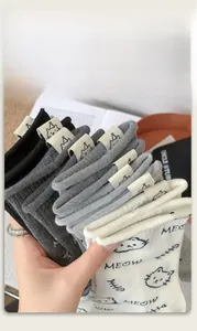 Close-up of cute cat-themed cotton socks featuring decorative woven labels and Meow prints