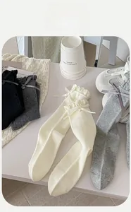 Detail of cotton crew socks featuring ruffle cuffs, ribbon bows, and button accents