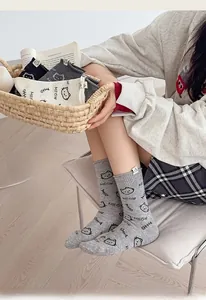 Detail of grey knitted mid-calf socks with cat embroidery and woven labels for women