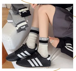 Detail of grey striped knitted mid-calf socks with woven label on ribbed cuff