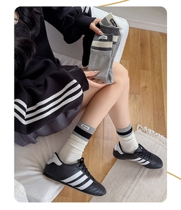 Detail of ribbed knit crew socks with logo labels in beige, light grey and dark grey colors