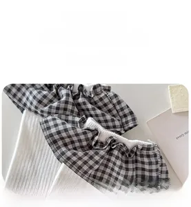 Detail of white ribbed socks featuring black and white plaid ruffle trim for women