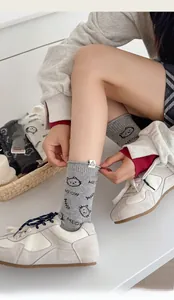 Close-up of light gray cotton socks with cartoon cat prints and MEOW lettering on side