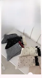Detailed view of polka dot socks with ruffled edges and M.E.K. letter fabric labels