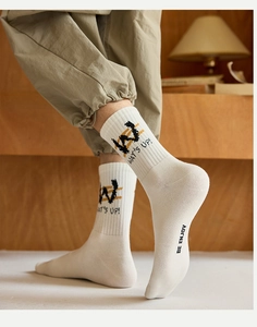 Detail of ribbed crew socks with WAT'S UP! graphic lettering on a warm cream cotton fabric