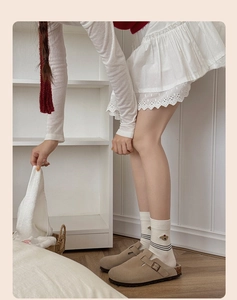 Détail de chaussettes en coton à rayures avec broderie ours et sabots en daim beige