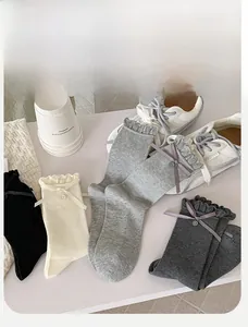 Detail view of cotton crew socks featuring ruffle trim, ribbon bows and decorative buttons