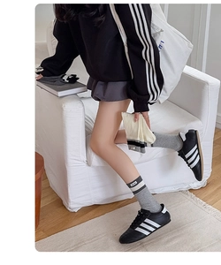 Close-up of grey mid-calf socks with contrast stripes and brand woven label detail