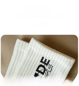 Detail shot of white knit socks with black letter print and elastic ribbed cuff