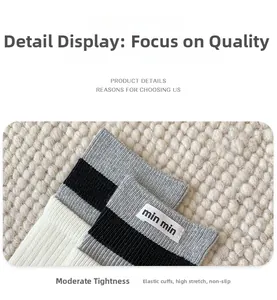 Close-up of ribbed grey and white crew socks featuring a woven logo label on the cuff