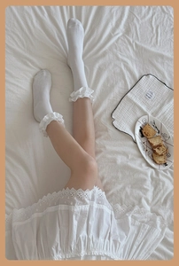 Detail of white cotton lace trim socks with frill edge shown in cozy home setting