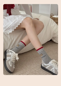 Détail de chaussettes grises avec chiot dessin animé et bord rouge avec baskets