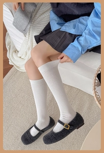 Close-up of white ribbed knee-high socks paired with grey plush Mary Jane shoes