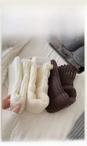 Détail de jambières en maille côtelée blanc, beige et marron avec bords ondulés élégants