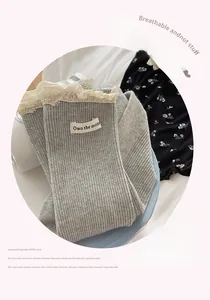 Close-up of grey ribbed crew socks featuring delicate lace trim and Own the moment label