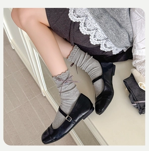 Detail of grey ribbed cotton socks with ruffled edges and dark grey silk ribbons
