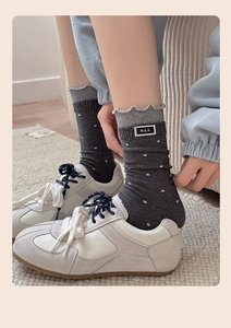 Close-up of polka dot crew socks with ruffle trim and textile label in white sneakers