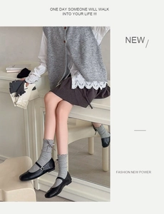 Close-up of Japanese style crew socks with ribbon bows and ruffle trim on grey knit fabric
