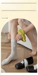 Close-up of light grey mid-calf socks with white 3D bow and heart mesh pattern