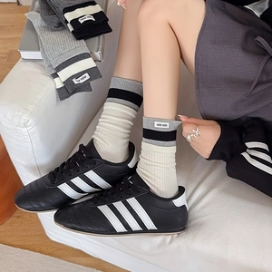 Gray patchwork mid-calf socks with contrast stripes and brand label shown in cozy setting