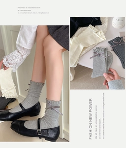 Detail of knit socks featuring ribbon bows, decorative buttons and ruffled cuffs