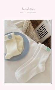 Close-up of ribbed knit cotton socks in cream white with colorful heart embroidery