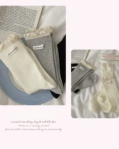 Detailed close-up of cotton crew socks with elegant lace trim and slogan fabric labels