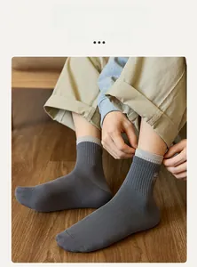 Detail of charcoal grey ribbed mid-calf socks with white rabbit embroidery on wood floor