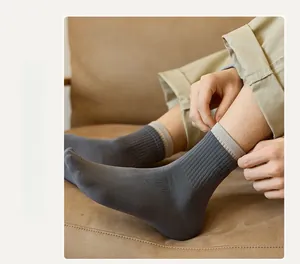 Detail of dark grey crew socks featuring layered color-block cuffs and fine embroidery