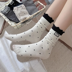 Polka dot crew socks with ruffle trim and logo tag shown in various neutral colors