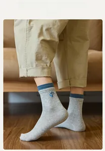Close-up of grey mid-calf socks featuring blue rib cuffs and cartoon embroidery detail