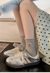 Detail of grey ribbed crew socks with pink bow accent and silver metallic sneakers