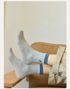 Close-up of men's crew socks showing navy blue ribbed cuff and small embroidery detail