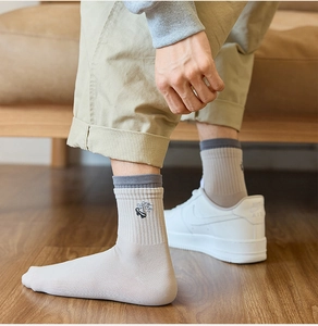 Detail of men's crew socks showing skateboard embroidery and ribbed cotton texture